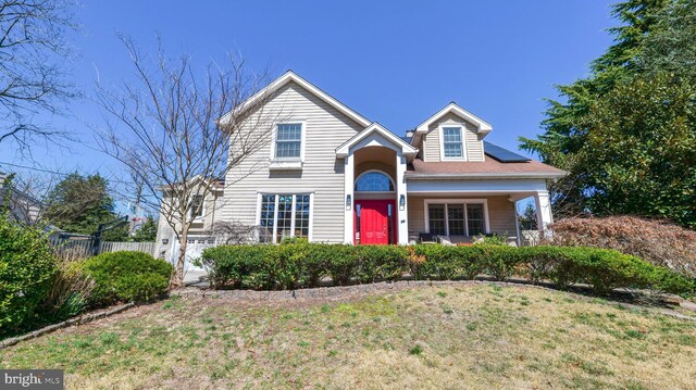 traditional-style home featuring solar panels, a front yard, and fence