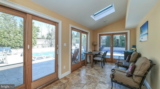 doorway to outside featuring vaulted ceiling with skylight, french doors, stone finish flooring, and baseboards