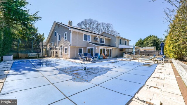 rear view of house with a fenced in pool, a patio, a chimney, and fence