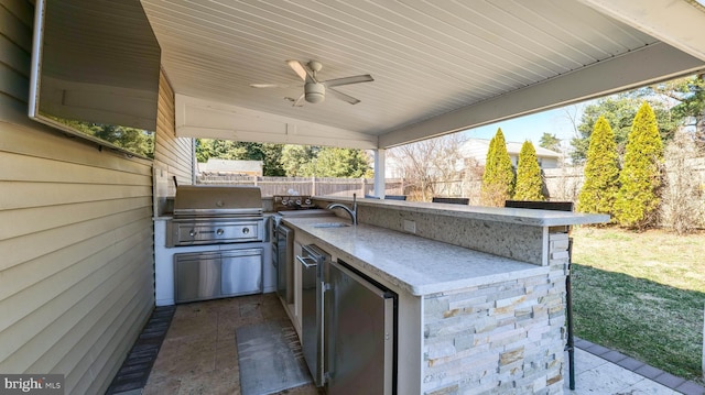 view of patio with a ceiling fan, a sink, a fenced backyard, a grill, and exterior kitchen