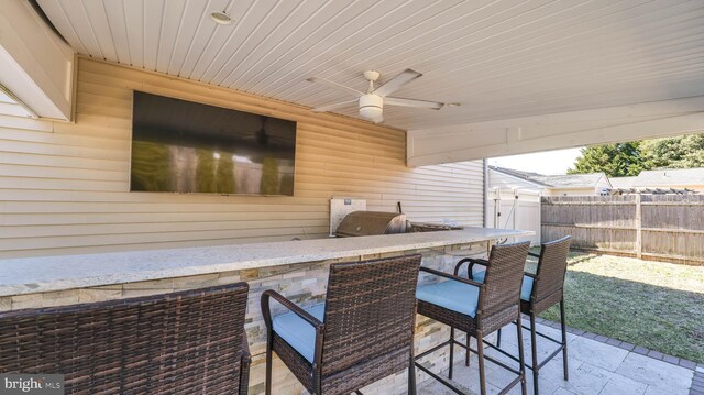 view of patio featuring a ceiling fan, fence, outdoor wet bar, area for grilling, and a grill
