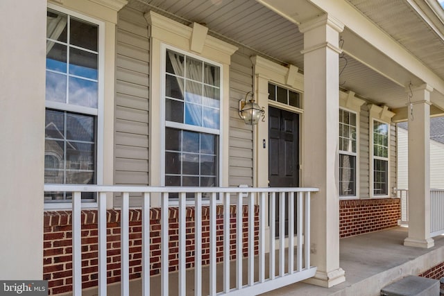 property entrance with a porch and brick siding