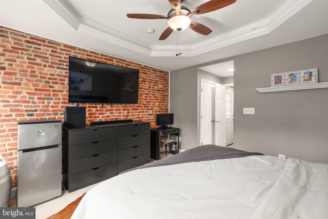 bedroom featuring a tray ceiling, freestanding refrigerator, and crown molding