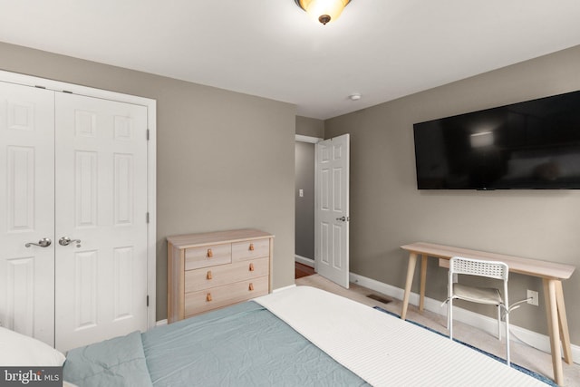 bedroom with baseboards, a closet, and light colored carpet