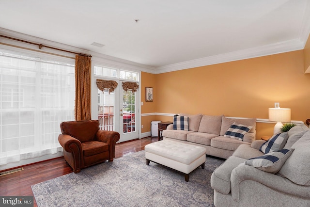 living room with crown molding, wood finished floors, baseboards, and visible vents