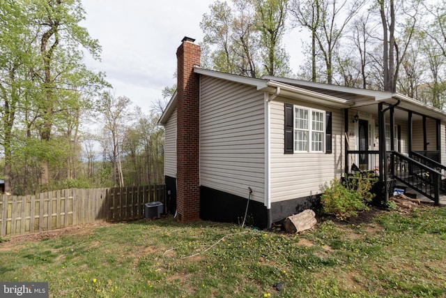 view of side of home with fence, a chimney, and central AC unit