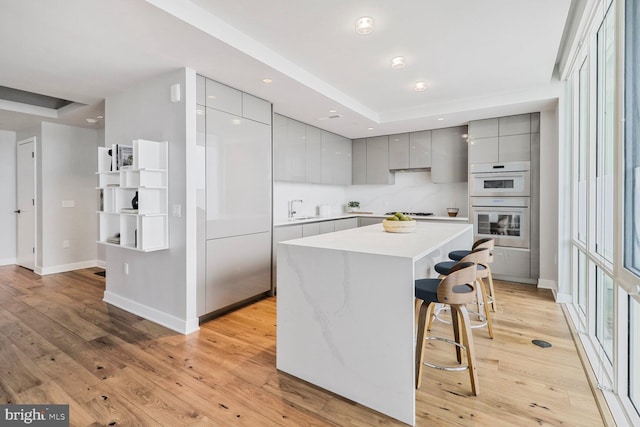 kitchen with gray cabinetry, baseboards, modern cabinets, and a kitchen bar