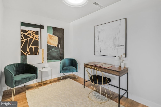 living area featuring visible vents, wood finished floors, and baseboards