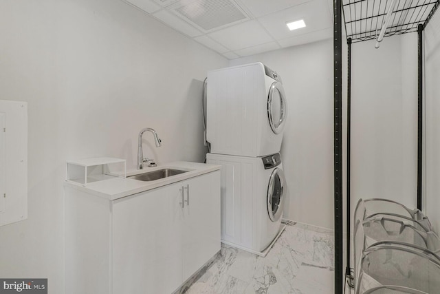 clothes washing area with stacked washer and dryer, cabinet space, marble finish floor, a sink, and visible vents