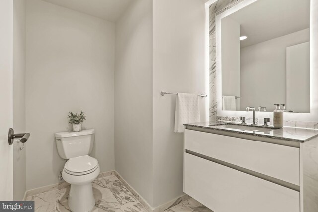 half bathroom featuring baseboards, toilet, vanity, and marble finish floor