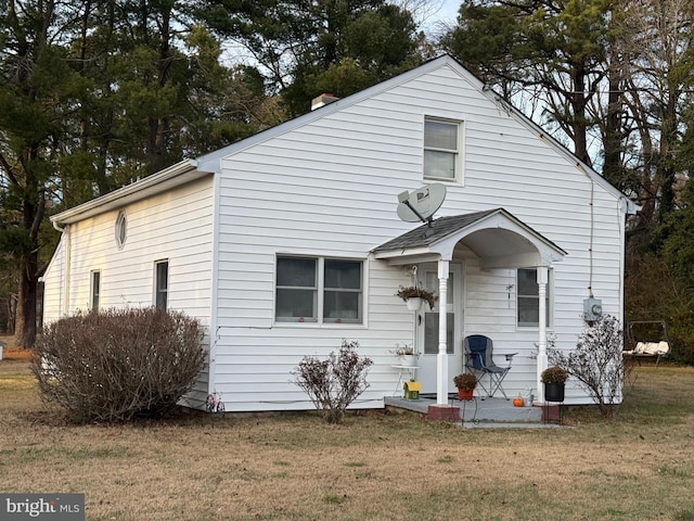 bungalow-style house with a chimney and a front yard