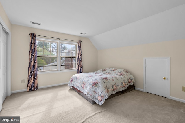 carpeted bedroom featuring lofted ceiling, baseboards, visible vents, and a closet
