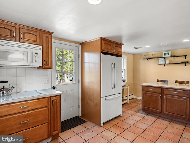 kitchen with white appliances, light tile patterned floors, brown cabinetry, decorative backsplash, and light countertops