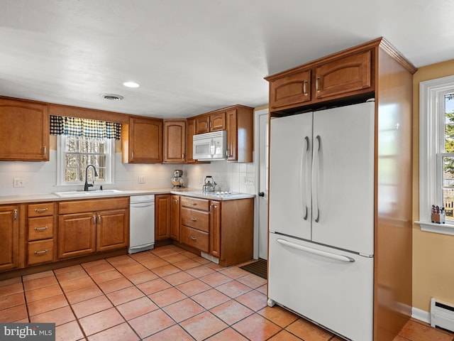 kitchen featuring visible vents, a baseboard heating unit, light tile patterned flooring, white appliances, and a sink