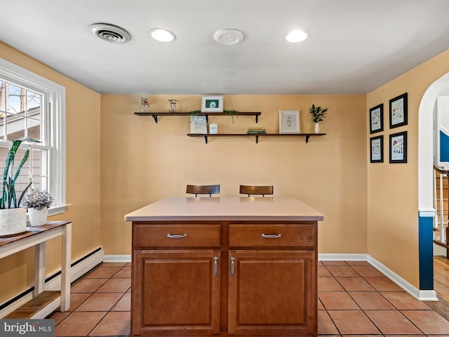 kitchen with light countertops, light tile patterned floors, arched walkways, and visible vents