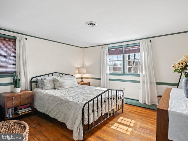 bedroom featuring visible vents, wood finished floors, and a baseboard heating unit