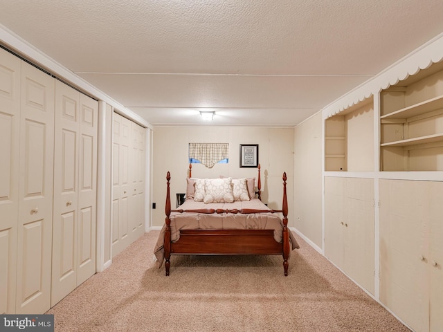 carpeted bedroom featuring baseboards, multiple closets, and a textured ceiling