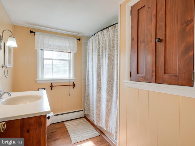 full bathroom featuring a shower with shower curtain, a baseboard radiator, wood finished floors, and vanity