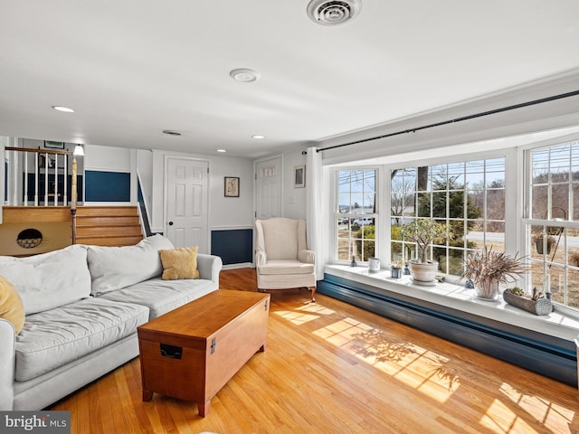 living area with stairway, recessed lighting, visible vents, and wood finished floors
