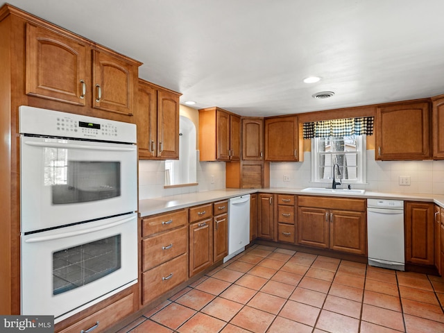 kitchen with decorative backsplash, brown cabinets, white appliances, and a sink