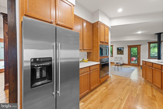 4544 30th St NW, Washington, DC 20008 - kitchen with black oven, light wood-style flooring, stainless steel fridge, and light countertops
