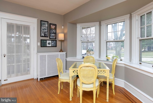 dining space with hardwood / wood-style flooring, radiator heating unit, healthy amount of natural light, and baseboards