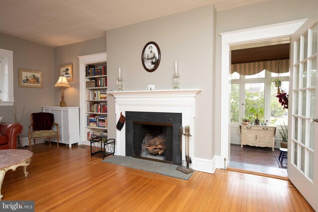 living room with hardwood / wood-style floors, a fireplace, built in features, and baseboards