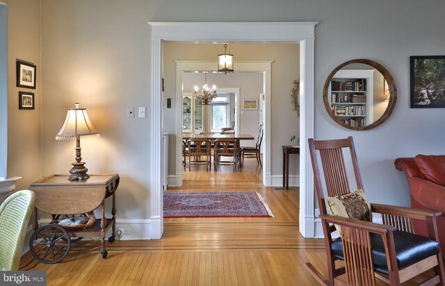 hallway with wood-type flooring, a chandelier, and baseboards