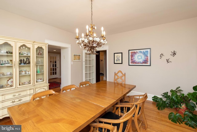dining room with a chandelier, light wood-style flooring, and baseboards