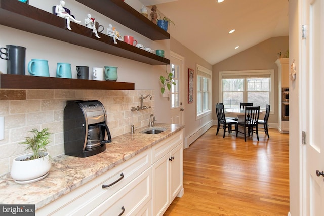 kitchen featuring open shelves, baseboard heating, tasteful backsplash, light wood-style floors, and vaulted ceiling