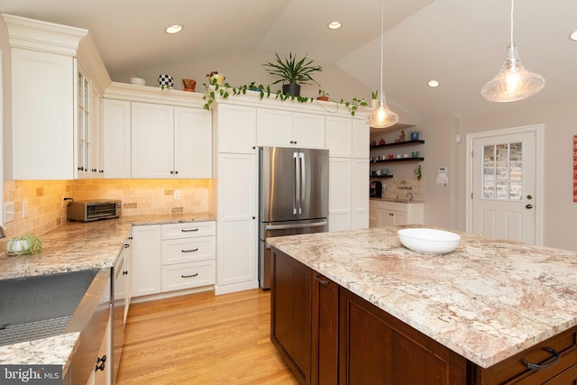 kitchen with stainless steel appliances, vaulted ceiling, light stone countertops, white cabinetry, and recessed lighting