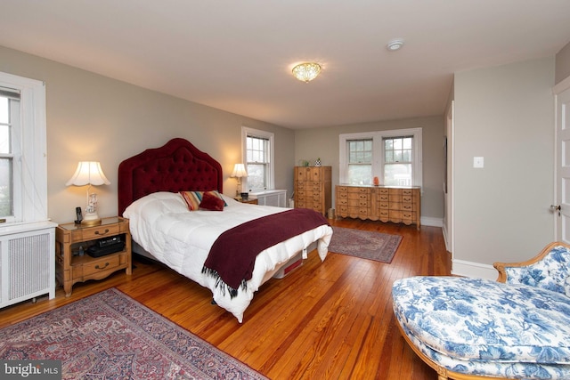 bedroom featuring radiator, wood finished floors, and baseboards