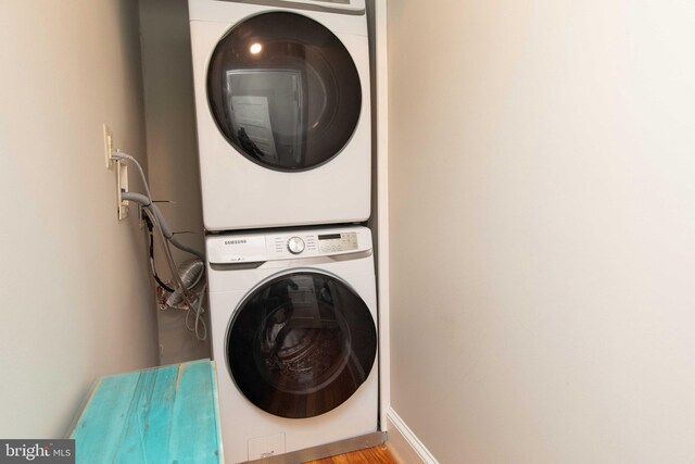 clothes washing area featuring stacked washer / dryer and baseboards