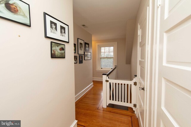 corridor featuring an upstairs landing, light wood-style flooring, and baseboards