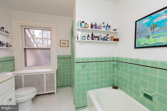 full bath with tile walls, a garden tub, radiator heating unit, a wainscoted wall, and tile patterned floors