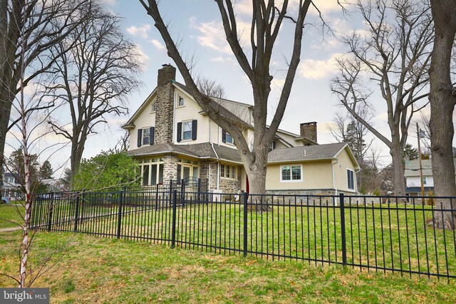 back of house featuring stucco siding, a chimney, and stone siding