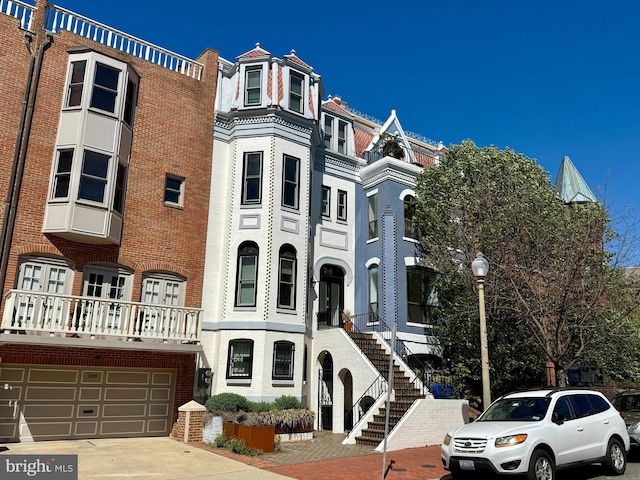 view of front of house featuring concrete driveway, stairway, a garage, and brick siding