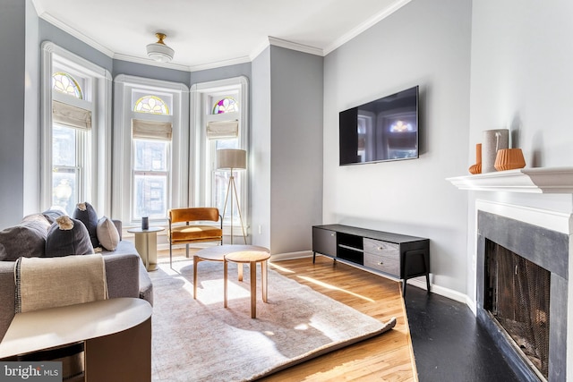 living room with a premium fireplace, baseboards, crown molding, and wood finished floors