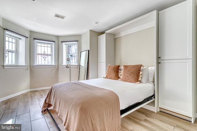 bedroom with light wood-style flooring, baseboards, and visible vents
