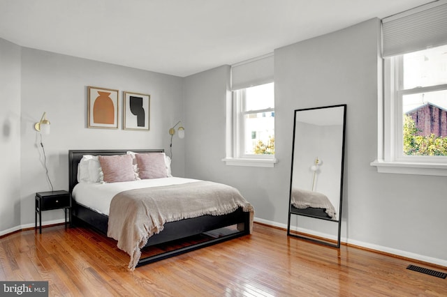 bedroom featuring wood-type flooring, visible vents, and baseboards