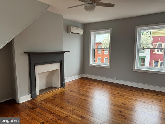 unfurnished living room with a ceiling fan, a healthy amount of sunlight, wood-type flooring, and an AC wall unit
