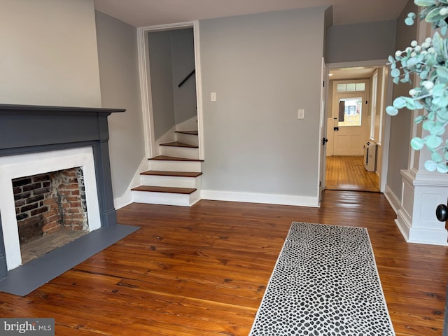 foyer entrance featuring baseboards, a fireplace, hardwood / wood-style flooring, and stairway