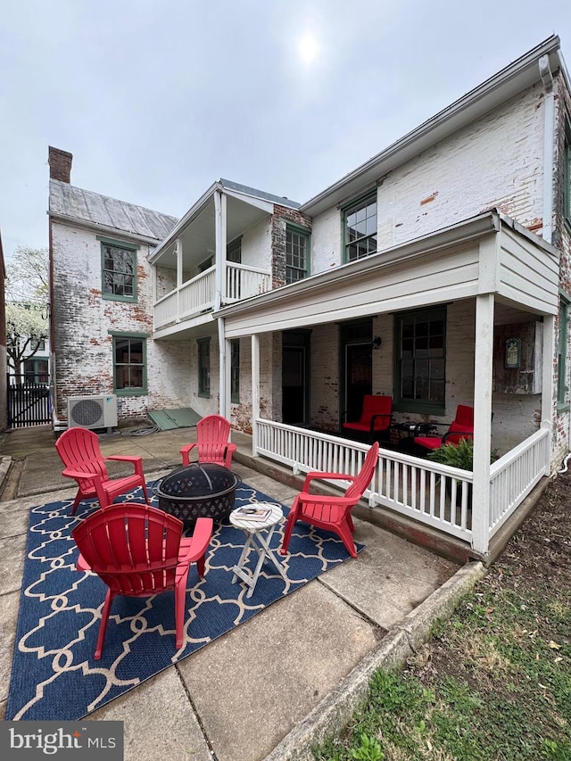 rear view of property featuring a patio area, ac unit, a fire pit, and a balcony