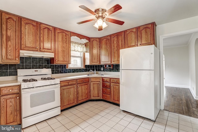 kitchen featuring under cabinet range hood, white appliances, brown cabinetry, and a ceiling fan
