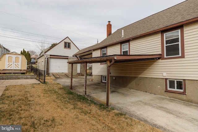 exterior space featuring fence, a chimney, an outdoor structure, a storage shed, and a lawn