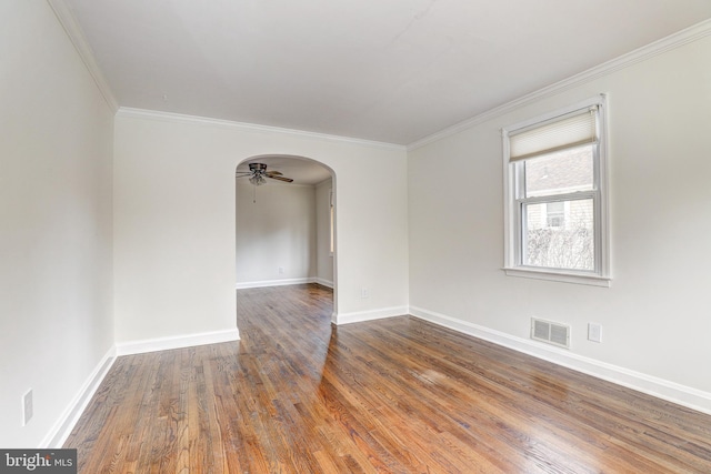 spare room featuring visible vents, a ceiling fan, wood finished floors, arched walkways, and crown molding