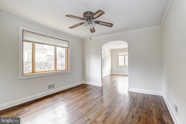 empty room featuring visible vents, baseboards, wood finished floors, arched walkways, and a ceiling fan