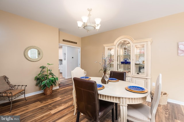 dining room with a notable chandelier, dark wood-type flooring, and baseboards