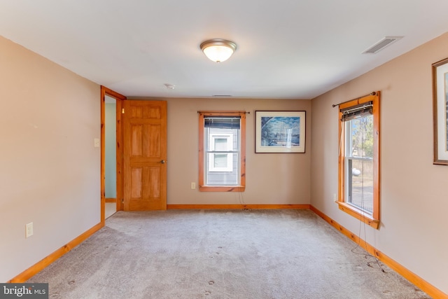 carpeted spare room featuring baseboards and visible vents