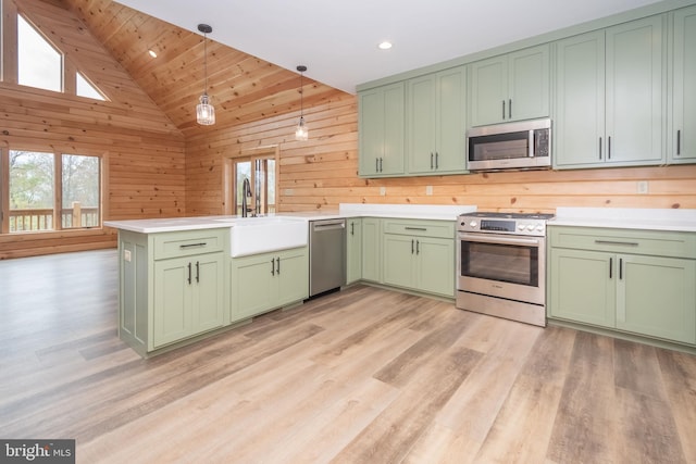 kitchen featuring green cabinets, stainless steel appliances, healthy amount of natural light, a peninsula, and vaulted ceiling